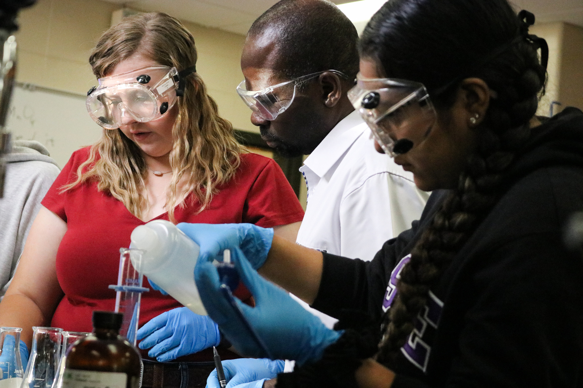 Students and professor measuring chemicals for experiment