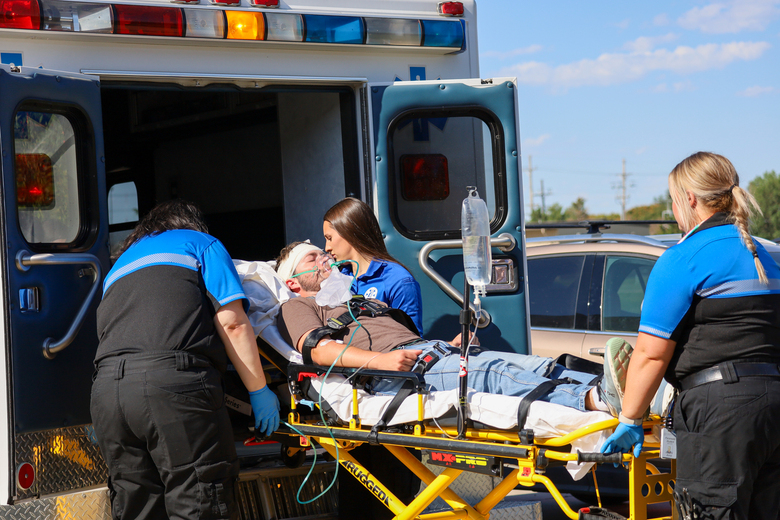 Students placing a man into a ambulence on a stretcher