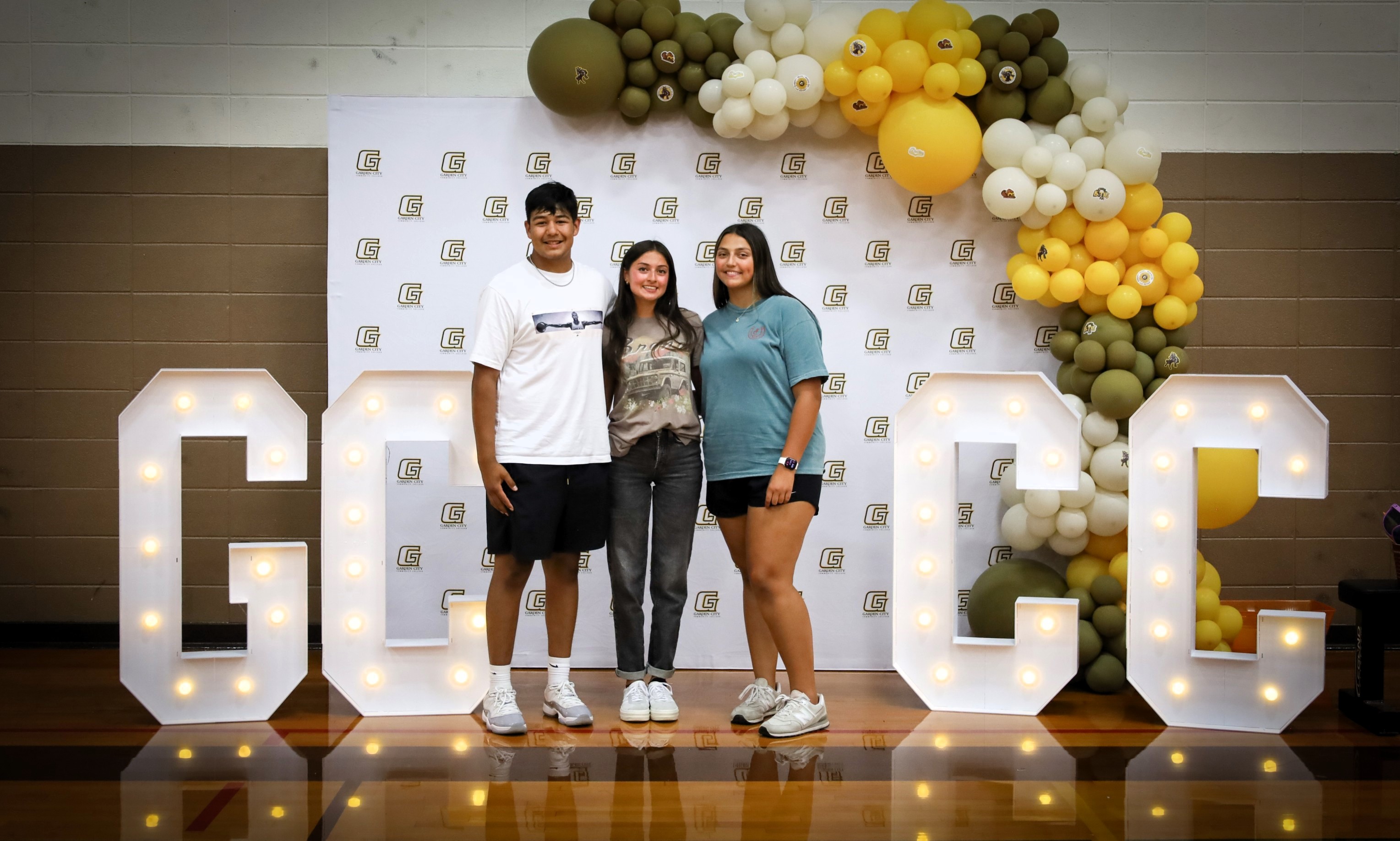 Students pose in front of illuminated GCCC letters and event decorations at campus orientation.
