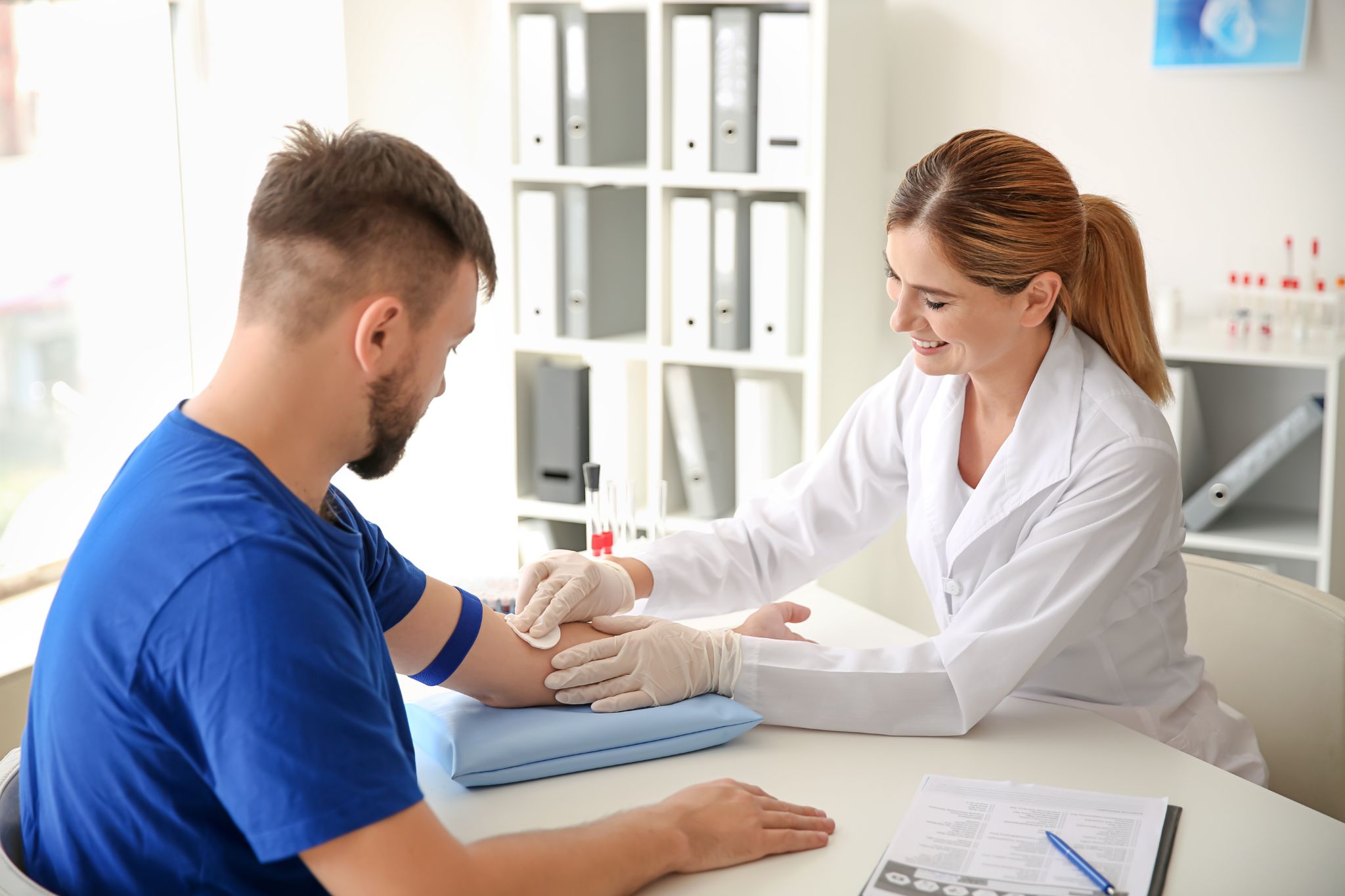 person drawing blood from patient in clinical setting
