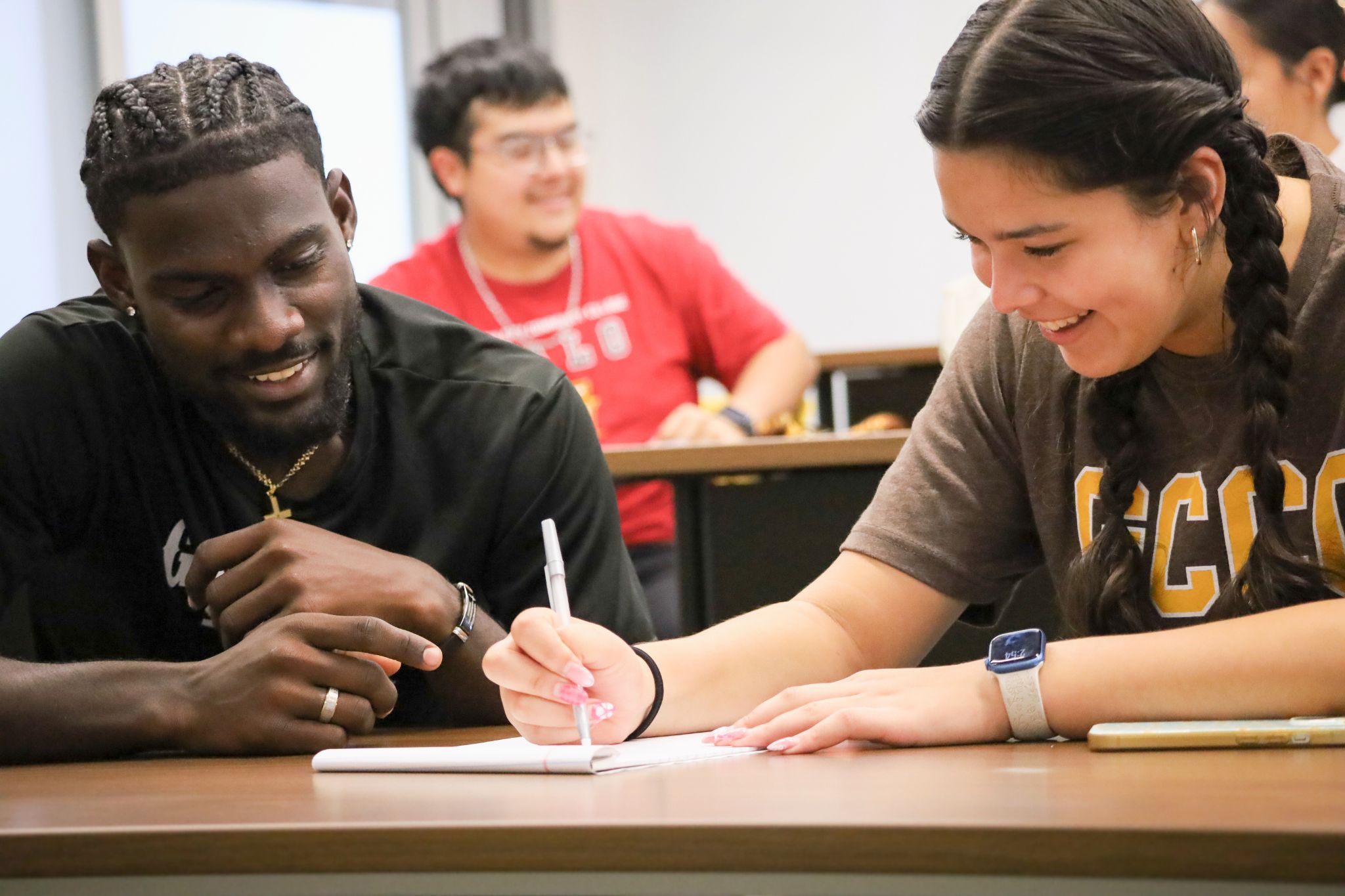 two students sitting at desk working on assignment