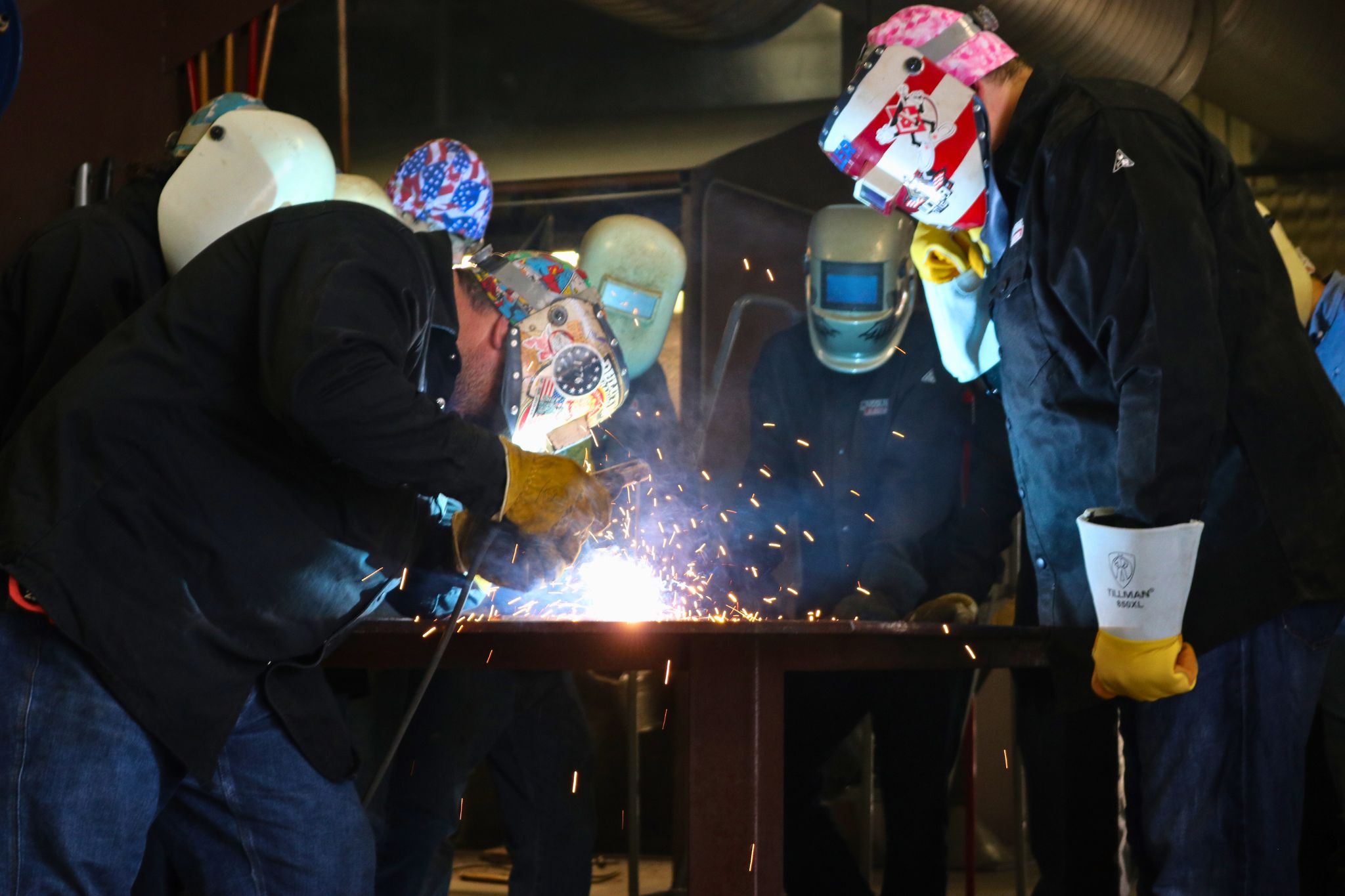 two welding students actively welding in lab