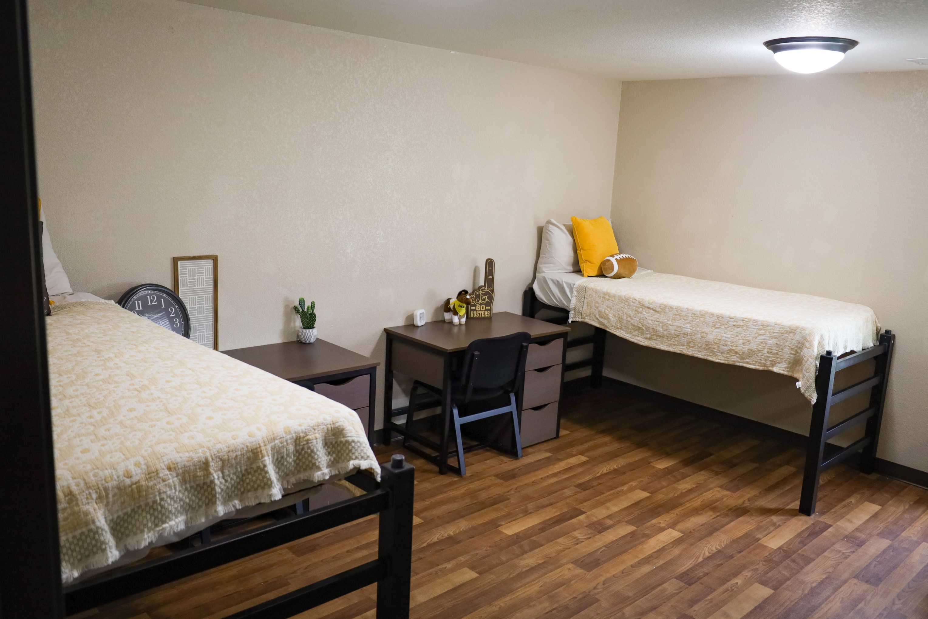 Bedroom with two single beds, small desks and chairs between them, and decorative items on the desks.