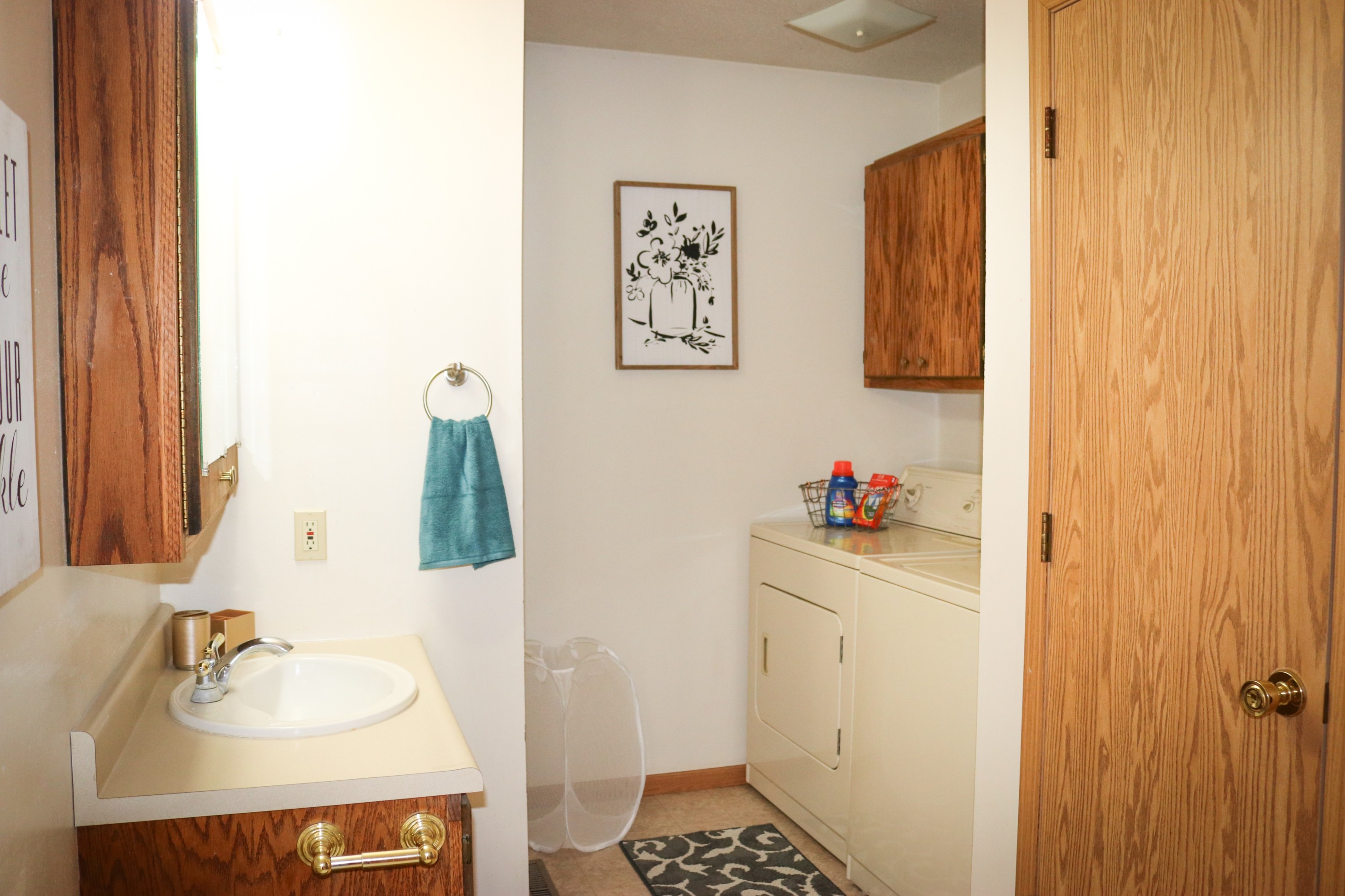 Small laundry area with a sink, washer and dryer, wood cabinets, and a towel hanging on the wall.