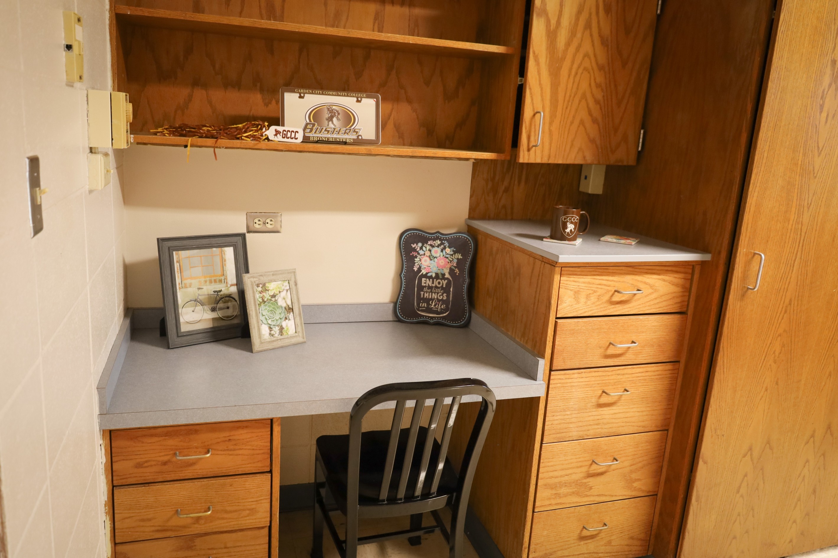 Wood desk with drawers and shelving, decorated with framed photos, sign, and small items, with a chair tucked underneath. Provide your feedback on BizChat